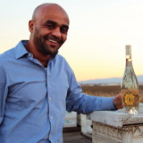 He shows off a bottle of Bee D’Vine honey wine and his book, <cite>The Celebrated Story of Honey Wine PHOTO: Molly Oleson