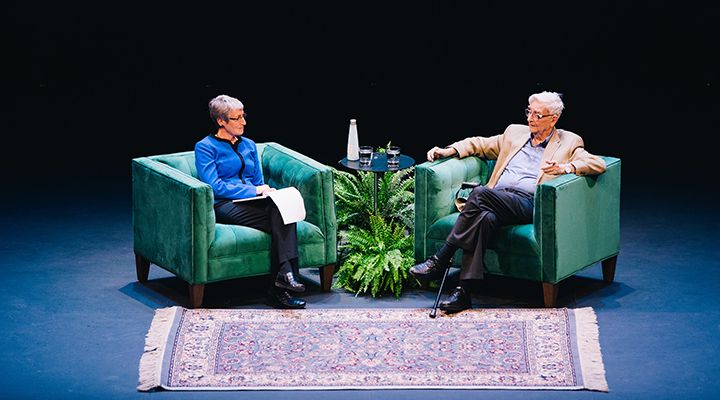 Two people sitting in chairs and talking to each other. 