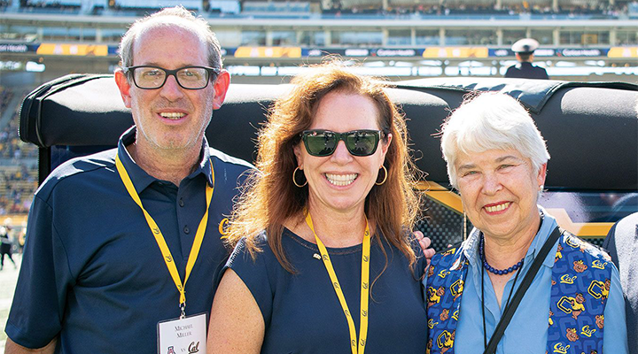 Three people standing at a football stadium.